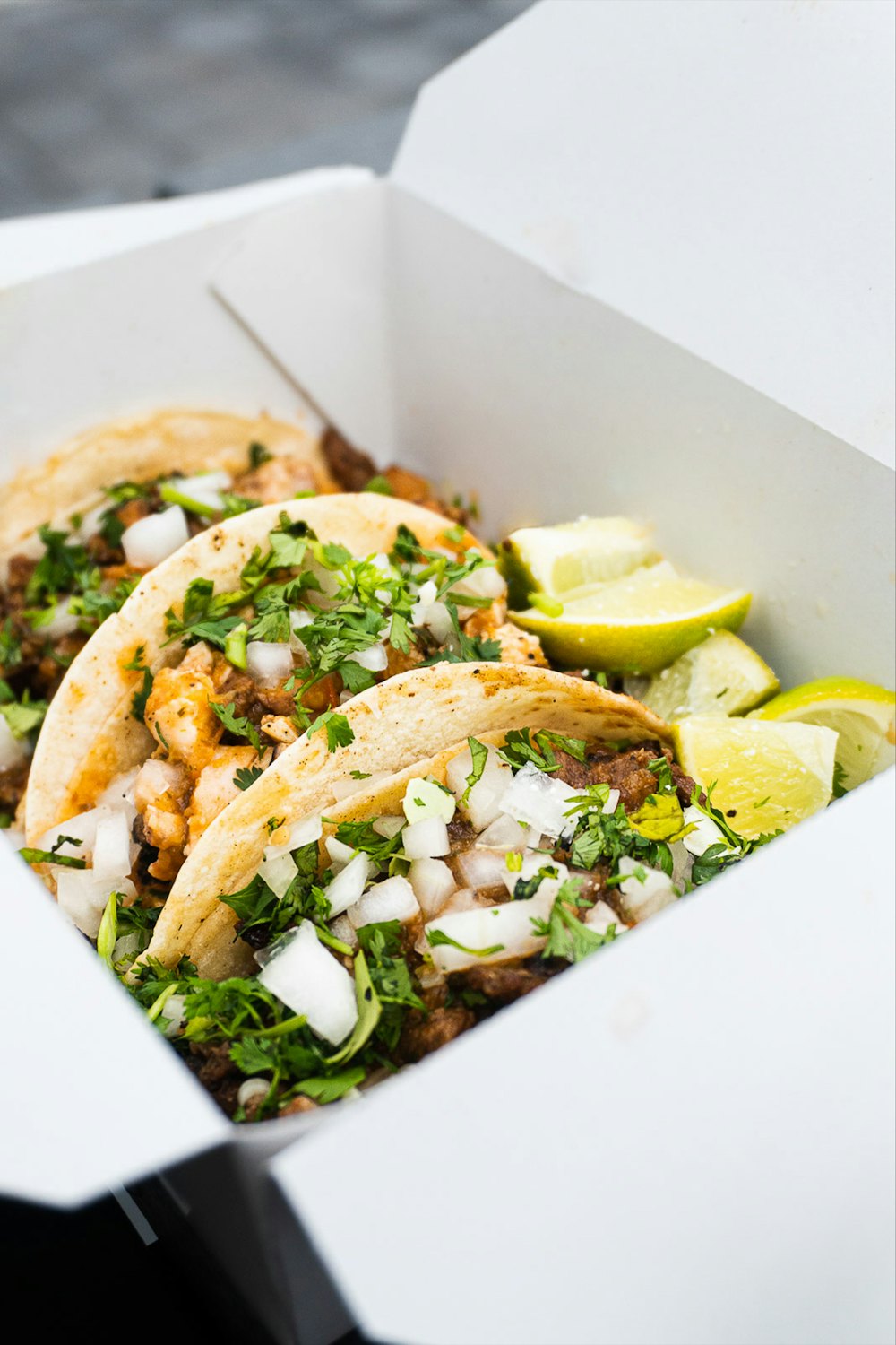 Stock photo of three tacos with lime in a box